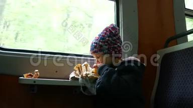 孩子在靠近窗户的火车上。 女孩吃馅饼，坐在火车上。